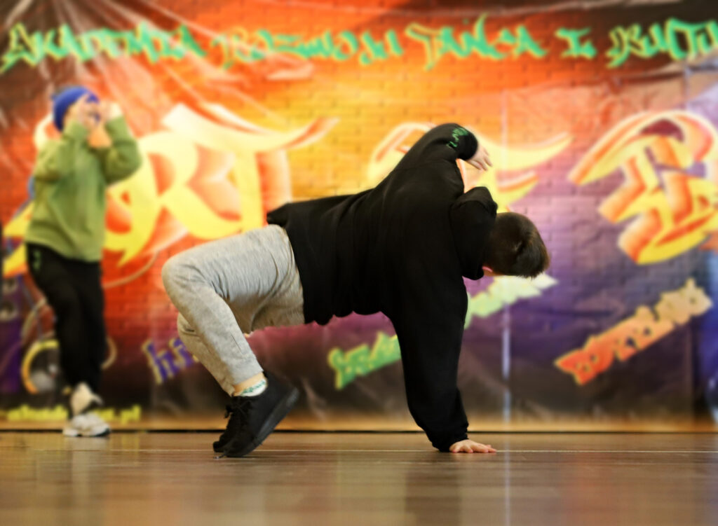 Young boy in black hoodie and grey joggers breakdancing