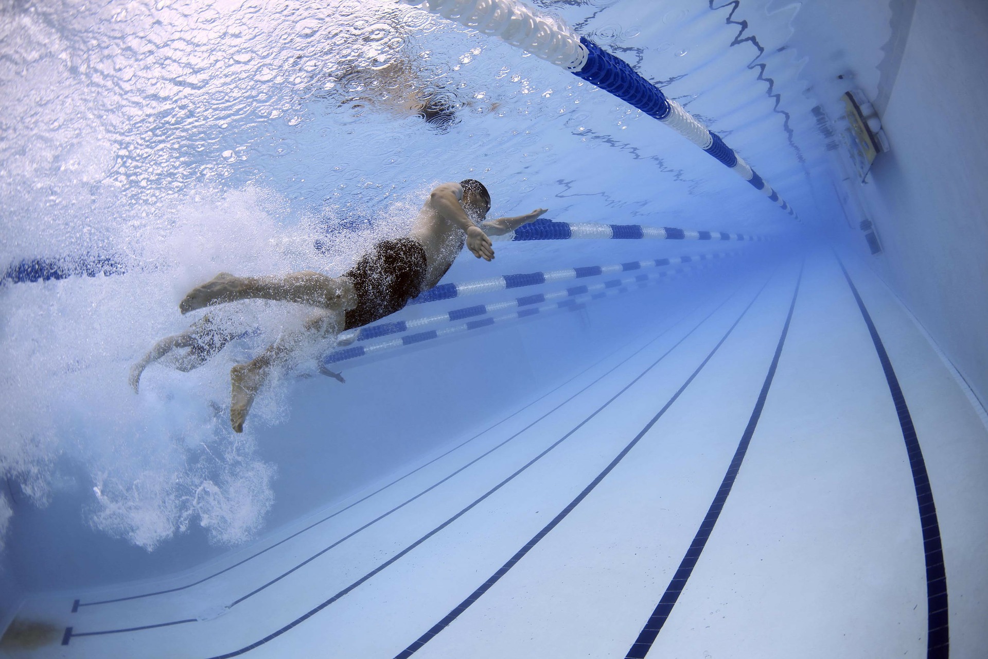 Male swimming in a swimming pool taken underwater.