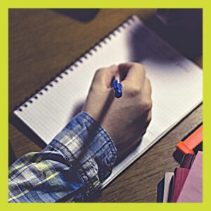 A4 notepad on desk with hand holding biro ready to write