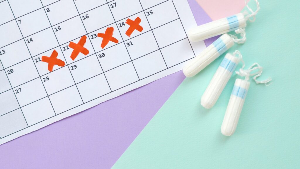 A calendar being marked off when on periods, with tampons next to it
