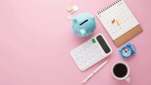 Flatlay of a calculator, coffee and piggy bank
