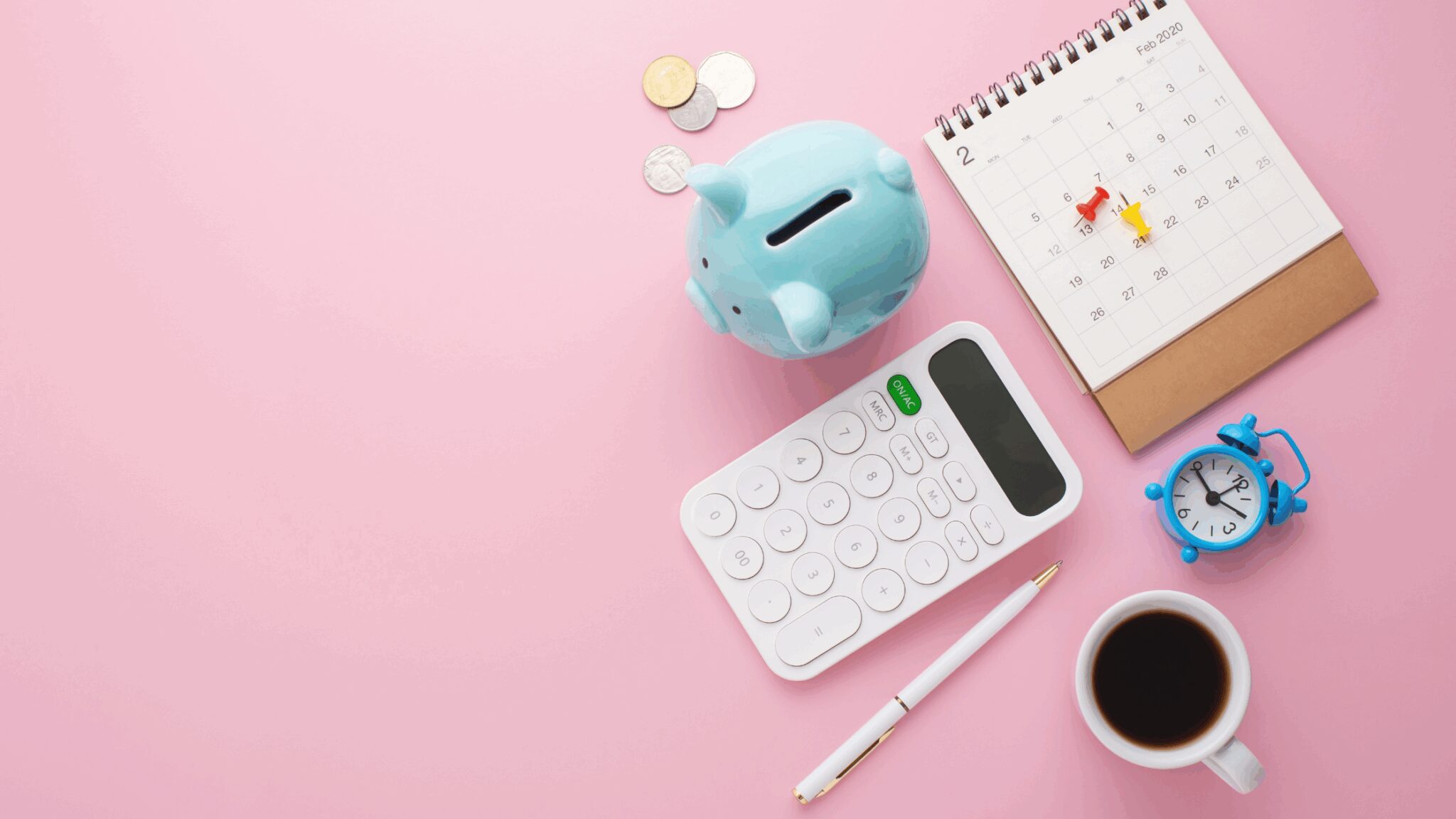 Flatlay of a calculator, coffee and piggy bank