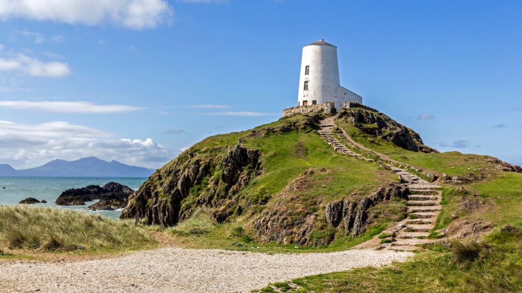 White lighthouse atop of a rocky and grassy hill