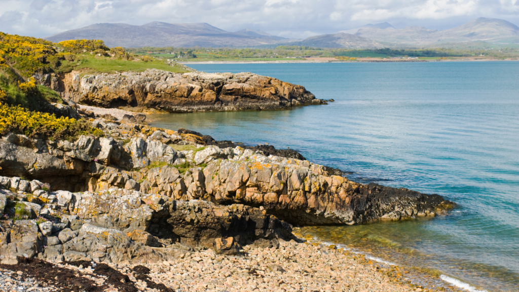 Rocky cliffs on beach, meeting with bright blue water