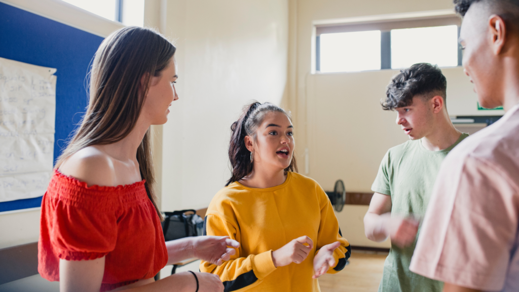 Four young people smiling and talking in an open room.  
University life