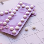 contraception - birth control pill with date of calendar background