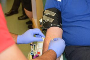 A nurse putting a needle into a blood donors arm