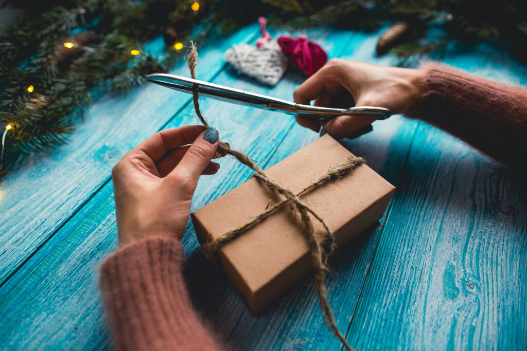 A person wrapping a present on a blue wooden table.