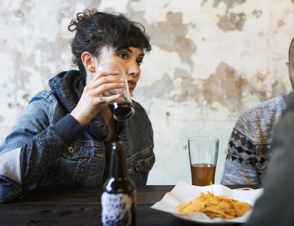 Two people sat at a table with beer bottles, after binge drinking
