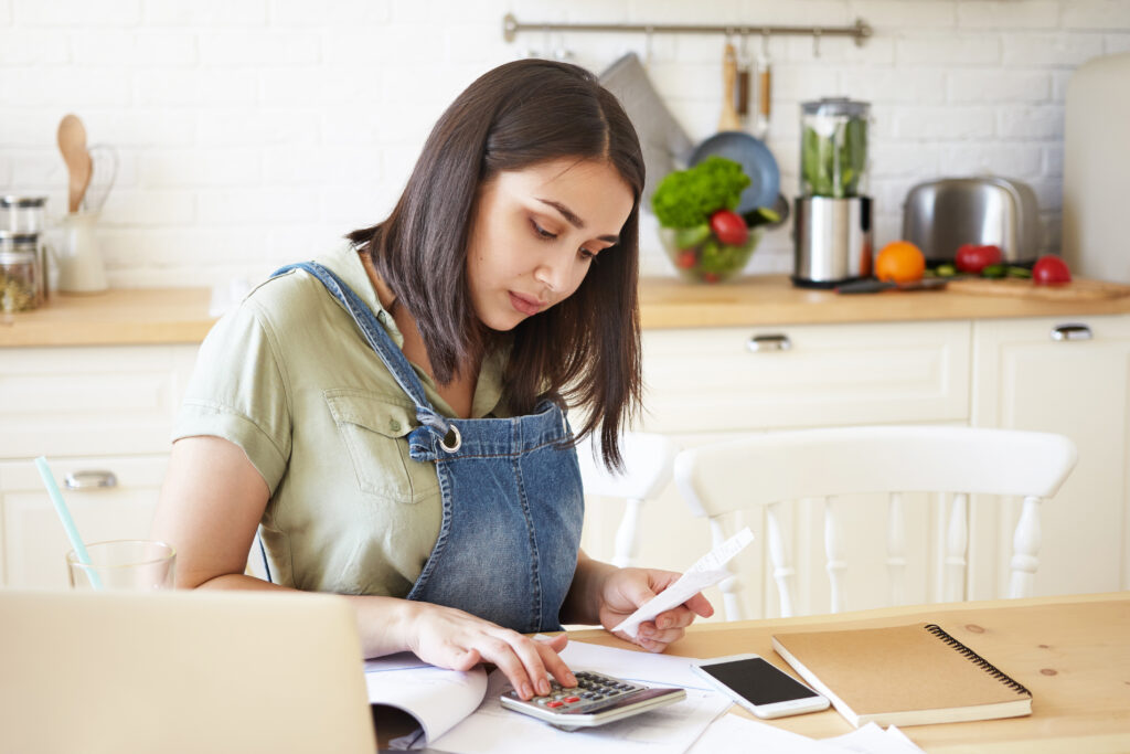 A women sitting at the kitchen table with a calculator. BNPL blog