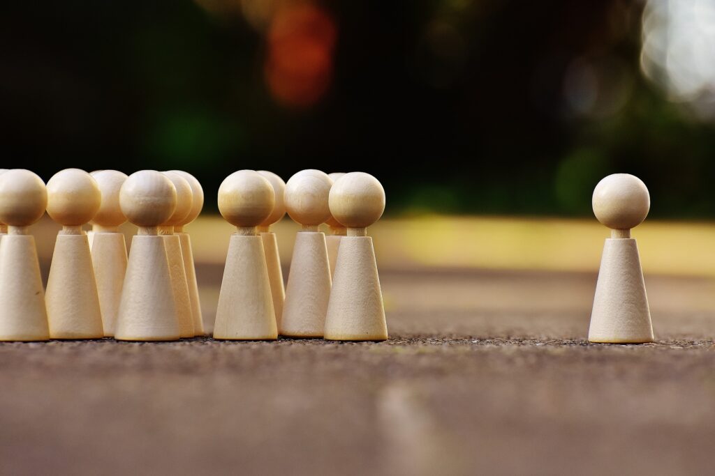 pawns from a chess set - a bunch together and one on it's own, separated, lonely