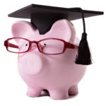 Pink piggy bank dressed as a college graduate with mortar board and glasses. Isolated on white.