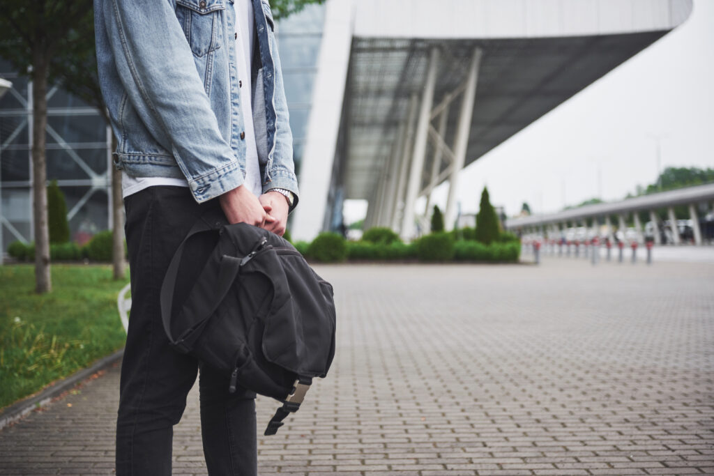 a person carrying a backpack waiting for a bus or train