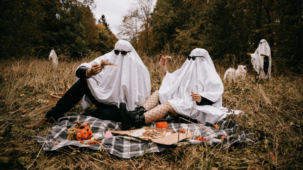 Two teens dressed as ghosts having a picnic