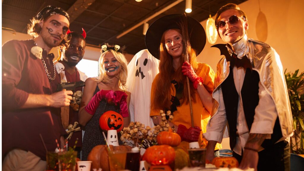 Group of young adults gathered together at a halloween party, all wearing different costumes, from pirates to ghosts 