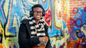 Black teenager in front of graffiti wall, smiling