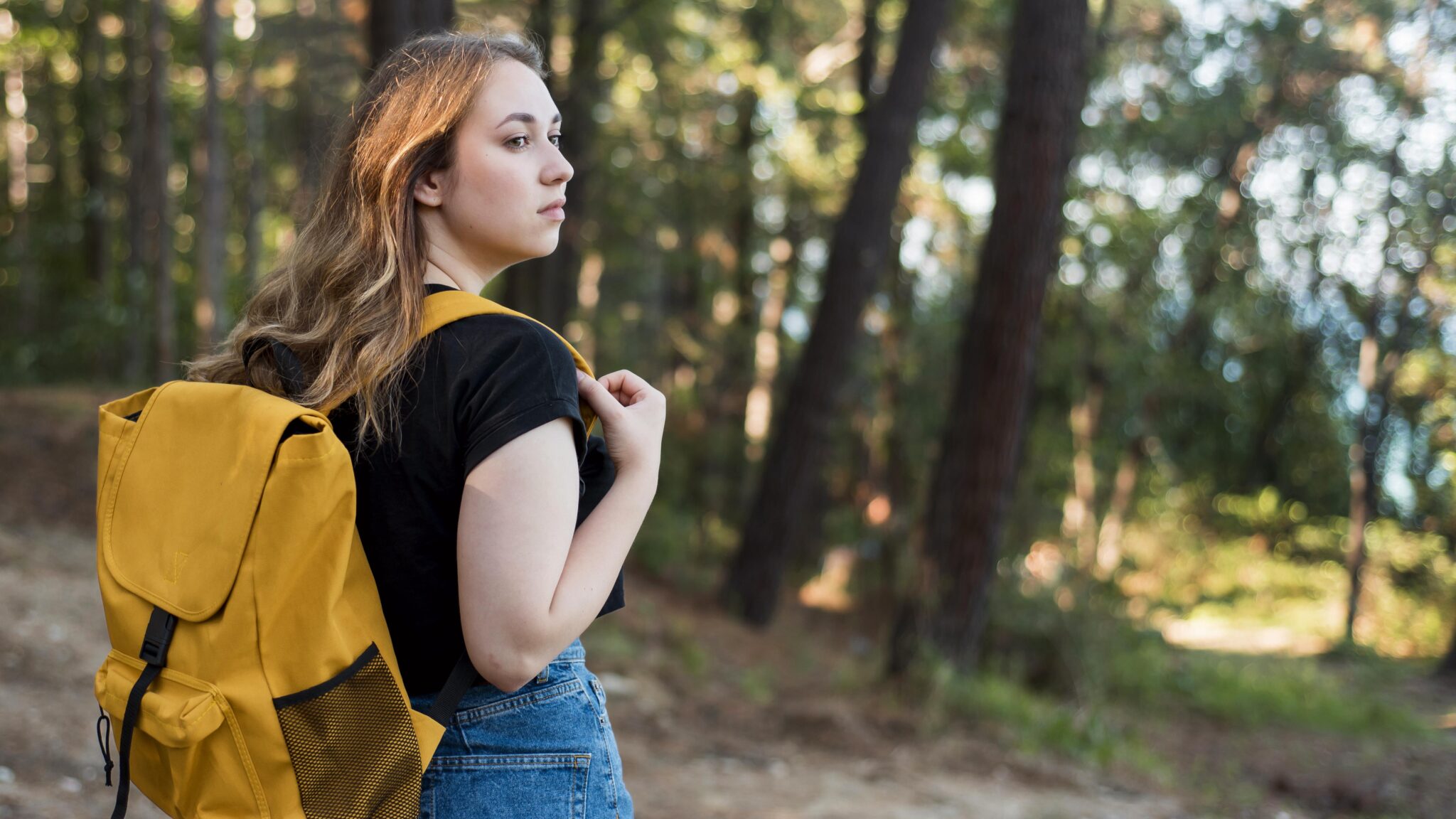 A young woman carrying a yellow backpack