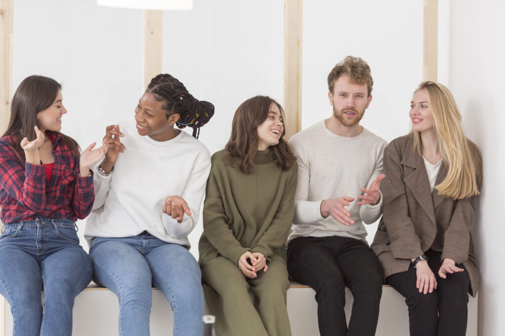 Five young people sitting on a ledge smiling and talking