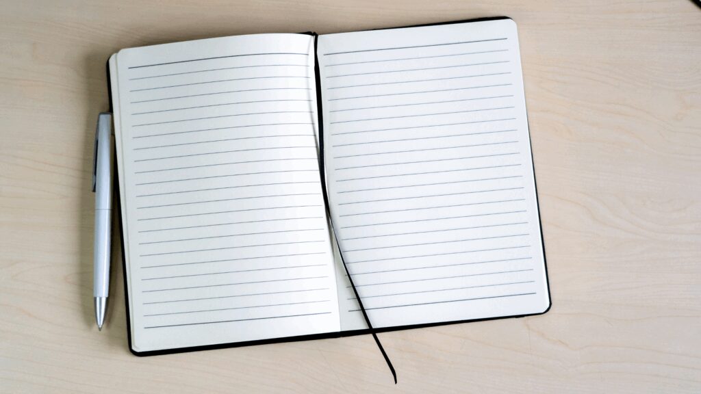 An empty open lined paper journey with a pen next to it