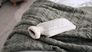 Hot water bottle on the blanket of a bed