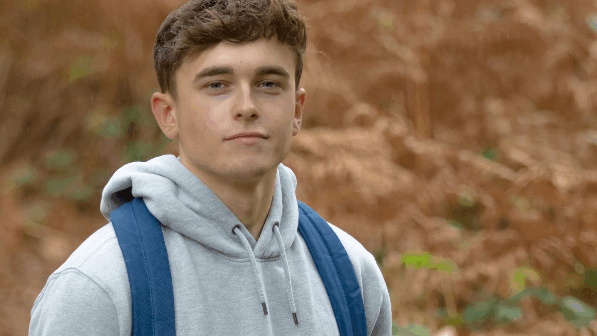 Young man stood ready with his backpack to leave outdoors