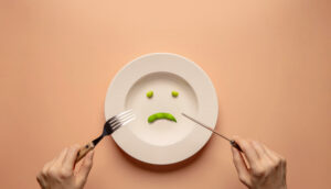 Young Woman Using Fork and Knife to Eating Green Soy Bean on Plate.
