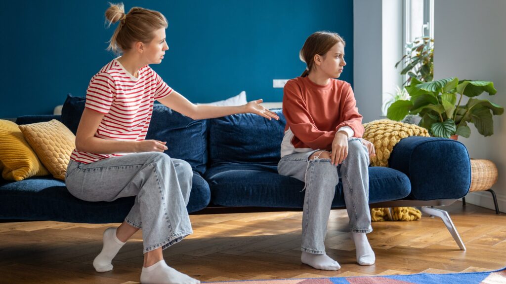 Mum shouting at teenage girl on a sofa whilst she looks away