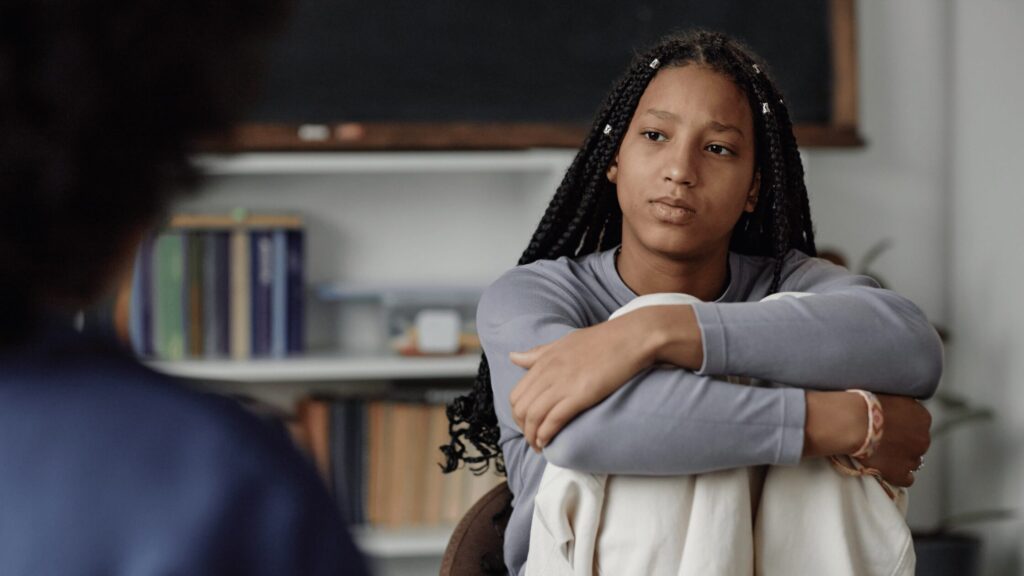 Girl sat on sofa talking to social worker