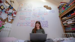 Teen girl revising alone in bedroom surrounding by revision notes