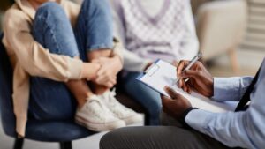Child sitting on sofa with their legs pulled up to their chest, talking to an adult