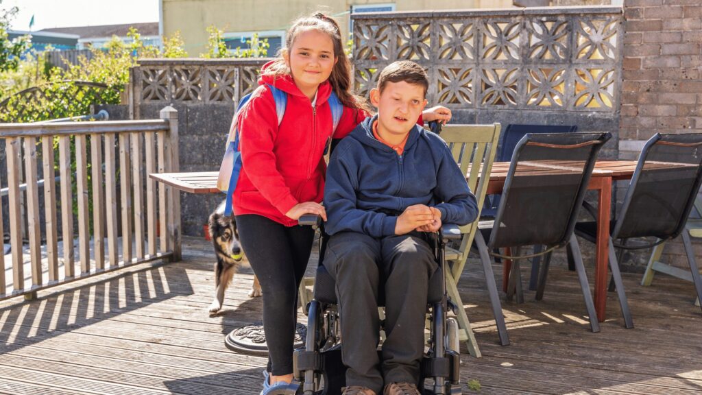 Young girl looking after her brother in a wheelchair