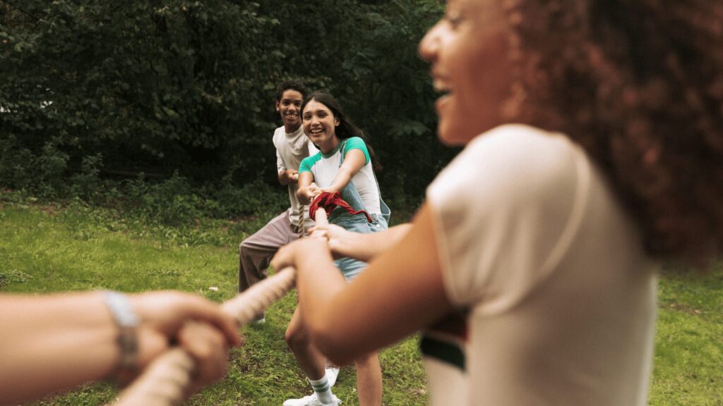 Friends playing tug of war in a field