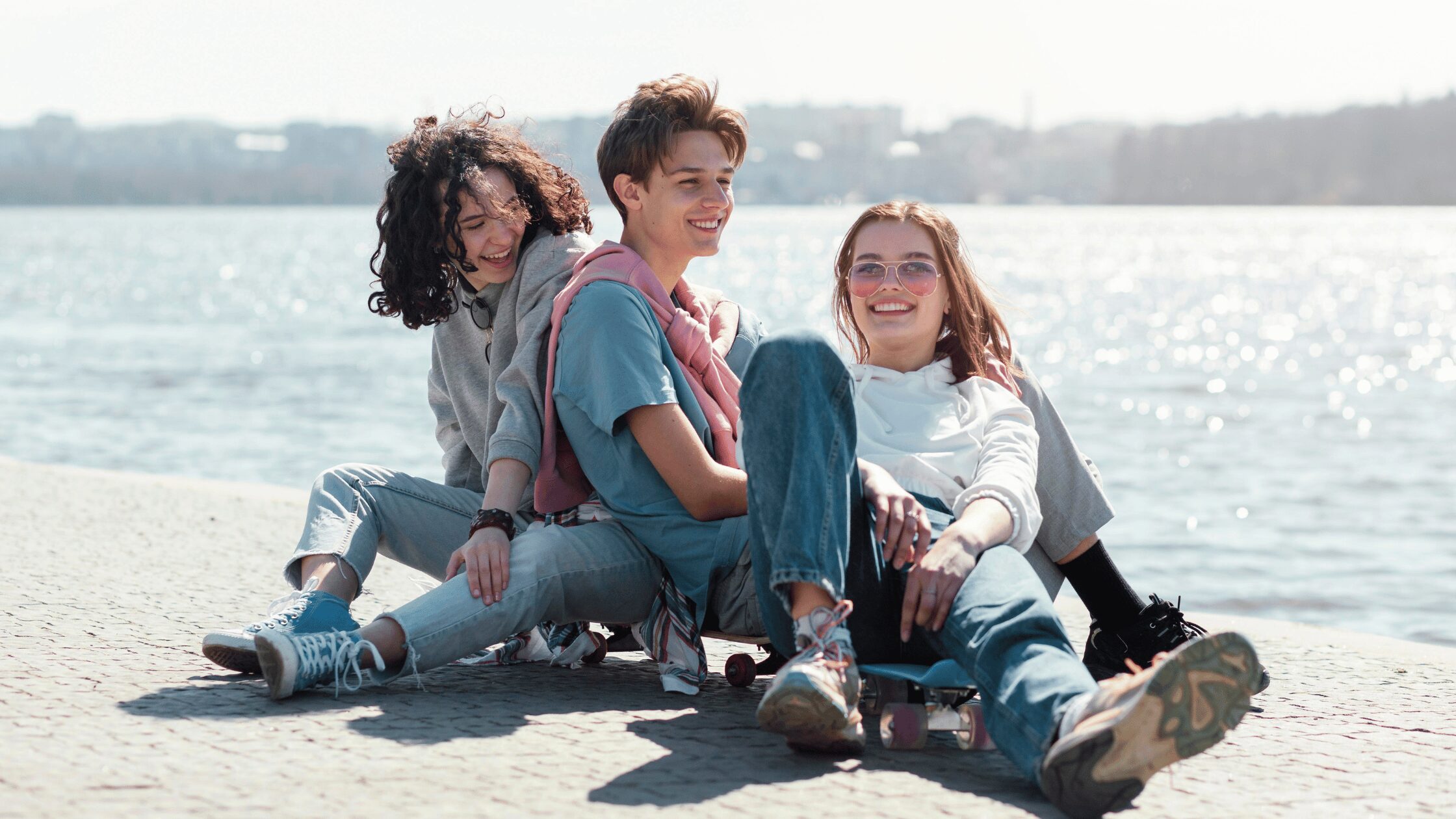 Three teens sat together at the seaside