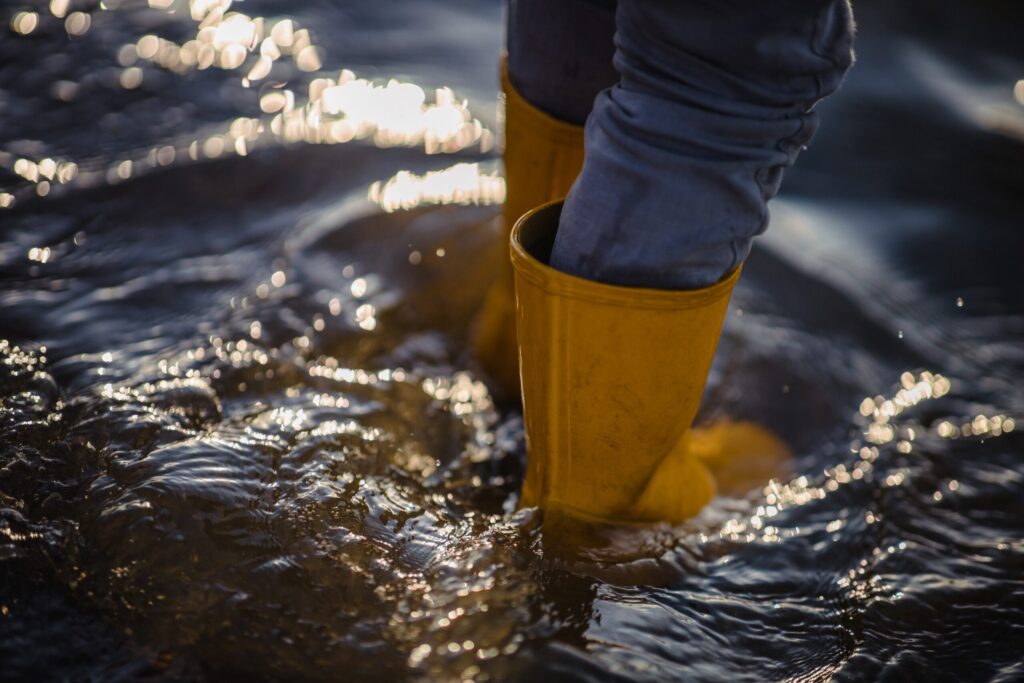 Person in blue denim jeans and yellow boots standing on water